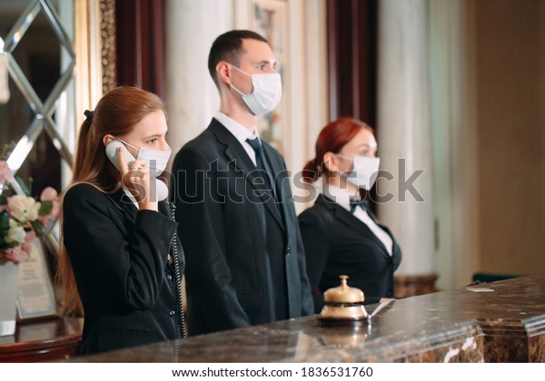 Check in hotel. receptionist\
at counter in hotel wearing medical masks as precaution against\
virus. 