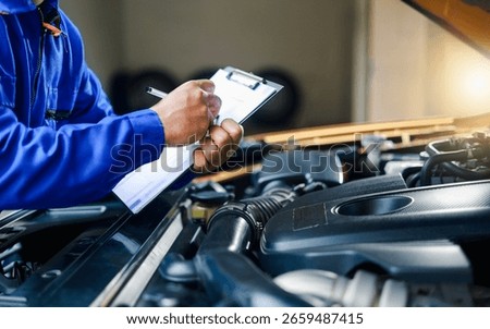 Check and inspect the condition of the car engine in detail. The mechanic is writing on a clipboard while looking at the car engine to assess the car's repair and maintenance.