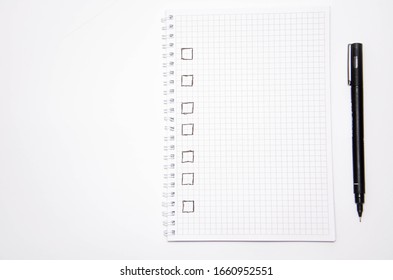 Check list. Square items are empty and checked with a tick. Squared notebook with black pen on a white background. Record ideas, notes, plans, tasks. Copy Space