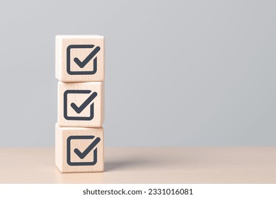 Check mark icons for jobs list on the face of wooden stacked blocks. Task lists, Checklist, Survey, Assessment, List, Confirm items, Double check, Quality Control. Goals achievement business success. 