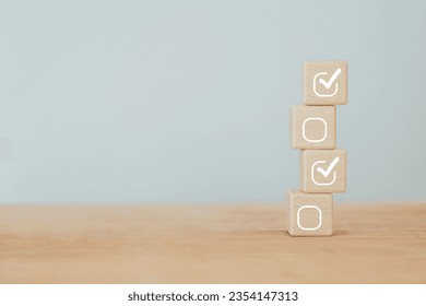Check mark icons for jobs list on the face of wooden stacked blocks. Task lists, Checklist, Survey, Assessment, List, Confirm items, Double check, Quality Control. Goals achievement business success