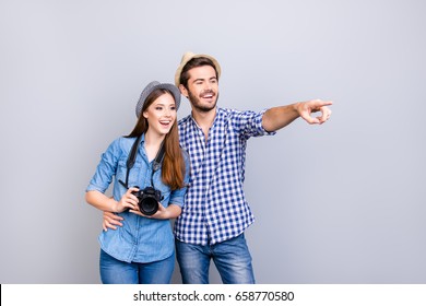 Check this out! Happy young couple of tourists are on vacation, in casual outfits, hats and with camera, isolated on pure background