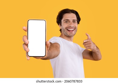 Check This Website. Portrait of smiling male holding smart phone with white blank screen in hand, showing device close up to camera and pointing finger at gadget with empty free space for mock up - Shutterstock ID 2060787833
