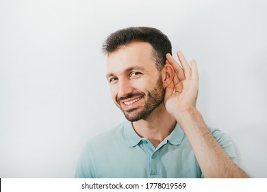 Check Your Hearing. Positive Man Holds His Hand Near His Ear, On A Gray Background. Ear Health, Treatment And Diagnosis Of Hearing