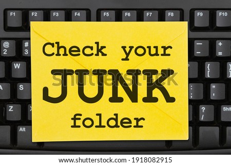 Check your junk folder message on a yellow envelope on a black keyboard 