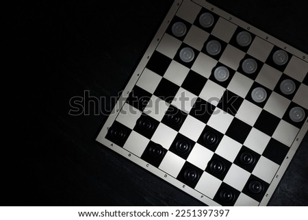 Checkerboard with game pieces on black table, top view. Space for text