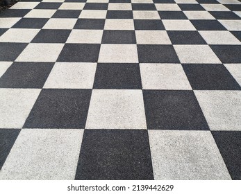 Checkerboard pattern surface, black and white. Grainy asphalt road surface. Close-up, top view, full frame.
