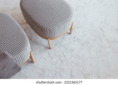 Checkered armchair with bench on wooden legs on a fluffy carpet, top view with copy space
