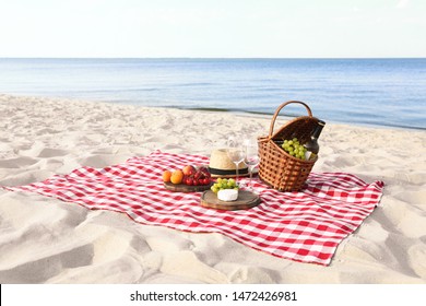 Checkered Blanket With Picnic Basket And Products On Sunny Beach. Space For Text