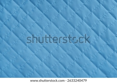 Checkered, diamond stitching pattern, blue quilted fabric background. Blanket or puffer jacket, stitch rhombus texture close up, macro. Wallpaper, backdrop.