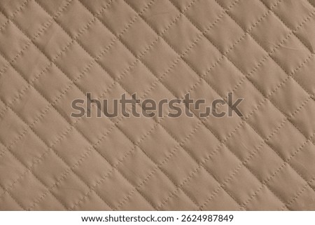 Checkered, diamond stitching pattern, brown quilted fabric background. Blanket or puffer jacket, stitch rhombus texture close up, macro. Wallpaper, backdrop.