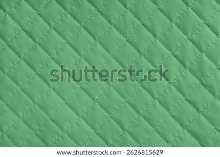 Checkered, diamond stitching pattern, green quilted fabric background. Blanket or puffer jacket, stitch rhombus texture close up, macro. Wallpaper, backdrop.
