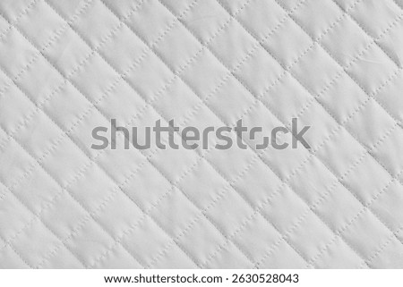 Checkered, diamond stitching pattern, white quilted fabric background. Blanket or puffer jacket, stitch rhombus texture close up, macro. Wallpaper, backdrop.