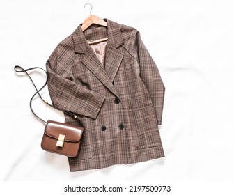 Checkered jacket in English style and brown leather cross body bag on a light background, top view   