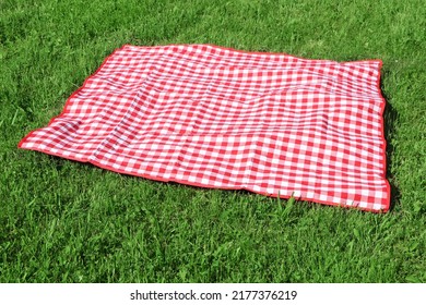 Checkered picnic tablecloth on fresh green grass outdoors - Powered by Shutterstock