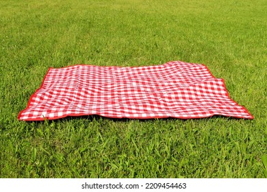 Checkered picnic tablecloth on fresh green grass outdoors - Powered by Shutterstock