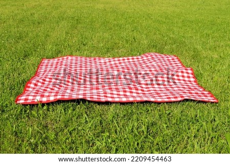 Checkered picnic tablecloth on fresh green grass outdoors