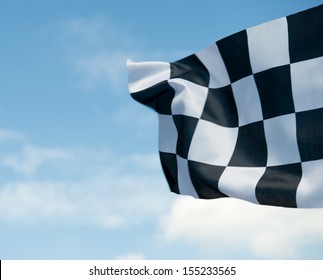 Checkered Race Flag Waving On Blue Sky.