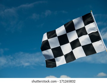 Checkered Race Flag Waving On Blue Sky.