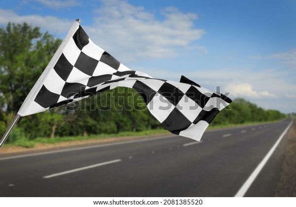 Checkered\
racing finish flag and asphalt road\
outdoors