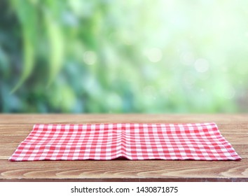 Checkered Red Picnic Folded Towel Cloth On Wooden Table Blurred Green Natural Background.Food Advertisement  Backdrop.