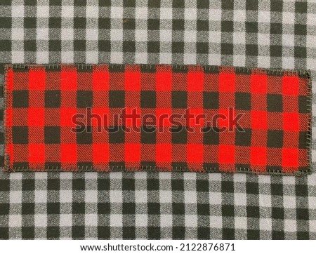 Checkered scarf on a background of black and white checkered fabric. Scarf top. Knitwear. Plaid. Wool fabric.