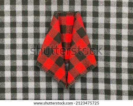 Checkered scarf on a background of black and white checkered fabric. Scarf top. Knitwear. Plaid. Wool fabric.