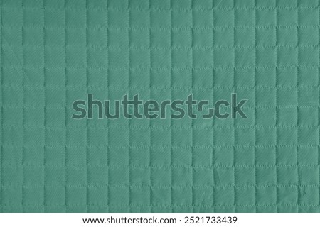 Checkered stitching pattern, green quilted fabric background. Blanket or puffer jacket, stitch square texture close up, macro. Wallpaper, backdrop.