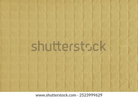 Checkered stitching pattern, yellow quilted fabric background. Blanket or puffer jacket, stitch square texture close up, macro. Wallpaper, backdrop.