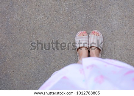 Checkered Warm Slipper with Pink Manicure Nails. Female Legs and Feet in Pink Pajamas and Slippers on The Cement Background Great For Any Use.
