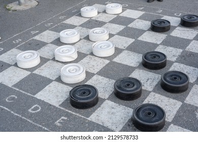 Checkers game. Gigantic black and white checkers on the asphalt.