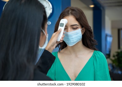 Check-in At The Hotel.Reception Wear Protective Face Mask Use Infrared Thermometer Checker Or Temperature Gun On Hotel Guest,Lifestyle New Normal After Corona Virus.