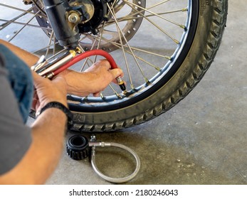Checking the air pressure on the front tire of an Adventure motorcycle with an air pressure gauge.