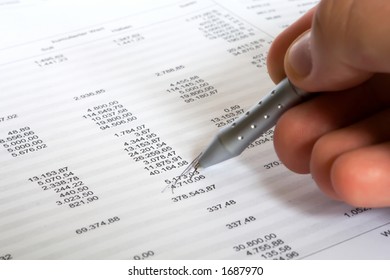 checking balance - man's hand holding pen and checking spreadsheet