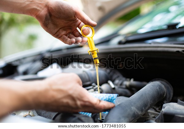 Checking car engine oil level with\
dipstick, under the hood of a car. Vehicle check-up.\
