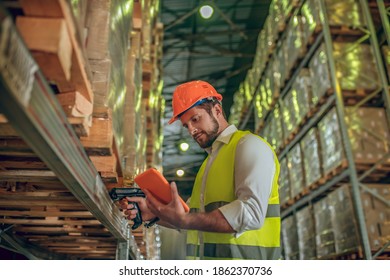 Checking data. Warehouse worker in yellow vest looking at the tablet - Powered by Shutterstock