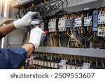 Checking the electrical system, an electrician is using an electric meter to check the electrical system at a control cabinet. for safety