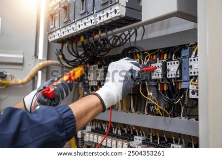 Checking the electrical system, an electrician is using an electric meter to check the electrical system at a control cabinet. for safety