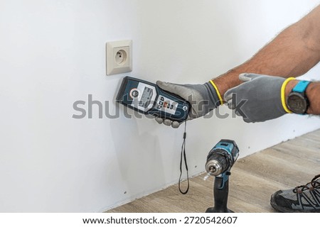 Checking for electrical wires in the wall before drilling holes using a wallscanner, metal detector.