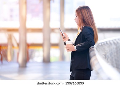 Checking email or text message from smartphone and take break to drink coffee while stand outside office workplace. Modernisation to use online mailbox innovation on mobile with faster communication 