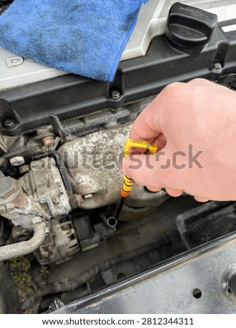 Checking engine oil level with yellow dipstick under the hood