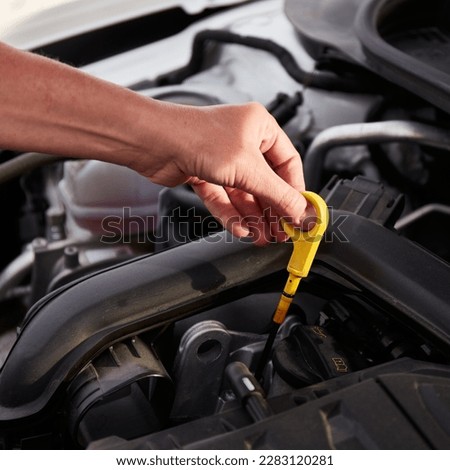 Checking engine oil. A woman's hand holding an oil bayonet in a modern popular car.