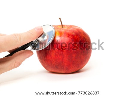 Checking, examination of apples, fruit. A man is examining a red apple with a stethoscope. Examination of fruit freshness. Quality control. Bio fruit. Best and proven apples. Isolated white background