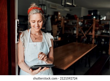 Checking future designs. Cropped shot of an attractive mature woman standing alone and using a tablet in her pottery workshop. - Powered by Shutterstock