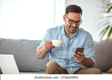 Checking his messages over coffee. Cropped shot of a handsome young man checking his messages while drinking coffee at home. Man using a smart phone while drinking coffee at home - Powered by Shutterstock