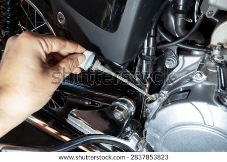 Checking motorcycle engine oil level with dipstick