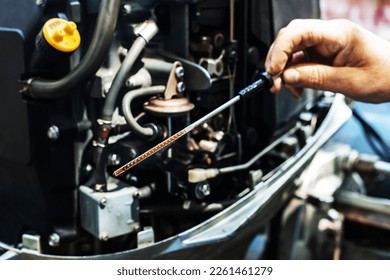 Checking the oil level in the boat engine. A dipstick with marks and an oil injector in the hands of a technical master. Close-up. unrecognizable person