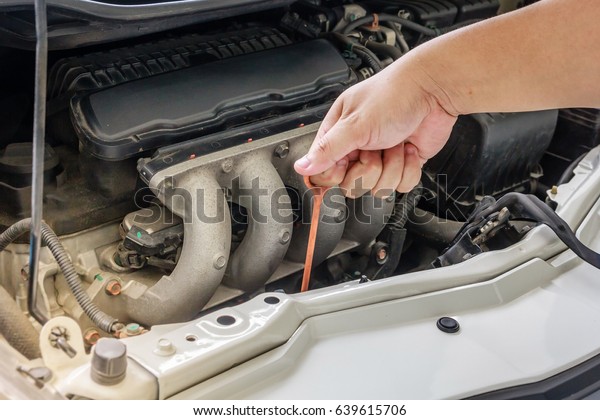 Checking\
the oil level in a car engine, Selective\
focus