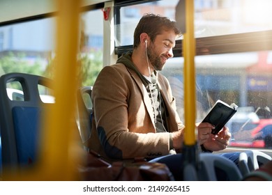 Checking out the best tourist spots. Cropped shot of a handsome young man reading a book during his morning bus commute.