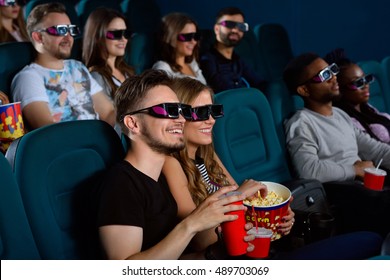 Checking Out A New Blockbuster. Shot Of A Happy Young Couple Having A Date At The Cinema Watching A 3D Movie Together Smiling Cheerfully 